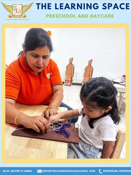 A teacher assists a young girl with her Eiffel Tower craft, ensuring she can successfully complete the project. My hands-on guidance helps build confidence and skill.