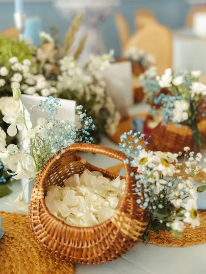 A wicker basket filled with white rose petals, ready for guests, showcasing a simple, natural, and thoughtful detail.