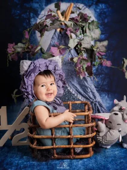 Celebrating the half-birthday milestone at six months old. This happy baby sits in a wicker basket with a '1/2' sign, showing off a huge, infectious giggle.