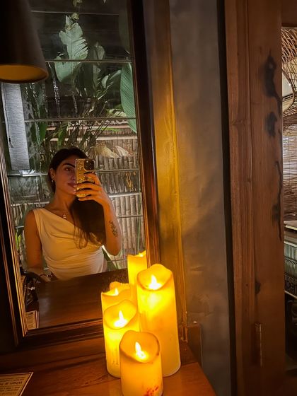 A quiet moment of self-reflection in a cozy, candle-lit space. Taking time to check in with myself, even with a quick mirror selfie, is part of my routine.
