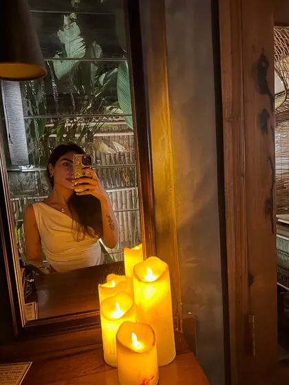 A candlelit mirror selfie from a Goa dinner. I wore a simple white cowl-neck top, which looks elegant in the soft light.