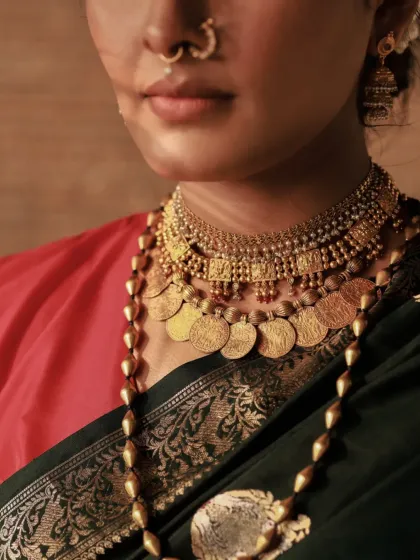 A close-up on the layers of traditional necklaces. This shot is perfect for showcasing the craftsmanship of the wedding jewelry and the richness of the bridal attire.
