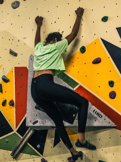 A participant in our workshop applies what she's learned, reaching for a hold on our colorful climbing wall. We focus on building confidence one move at a time.