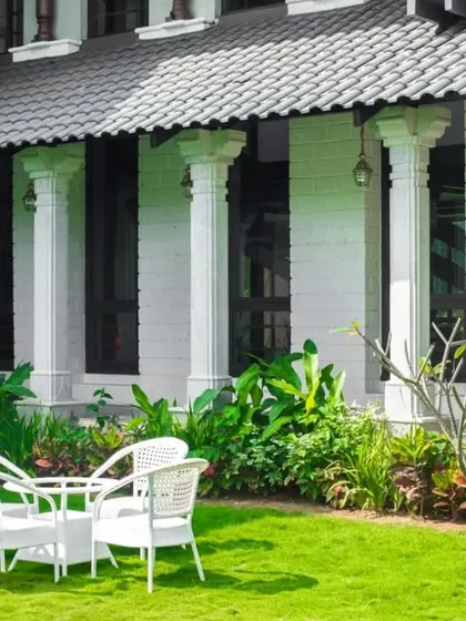 A classical farmhouse exterior with a manicured lawn and outdoor seating, perfect for enjoying a cup of tea in the garden.