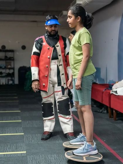 A coach provides instruction to a young athlete on balance boards, a key part of our holistic training regimen.