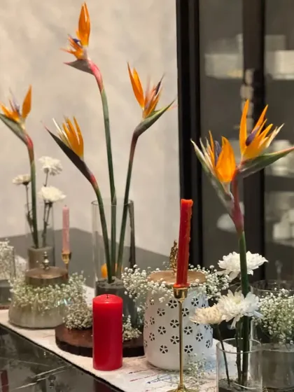 Bringing the art of tablescaping to life by transforming a table setting into a piece of art. Here, exotic 'bird of paradise' flowers are paired with simple white blooms and colorful candles for a modern and dramatic effect.