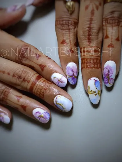 A similar watercolor floral design with gold accents, shown here with delicate henna.