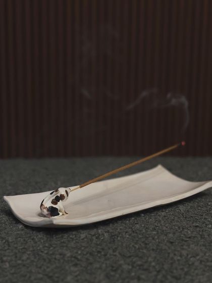A minimalist incense holder featuring a tiny, spotted dog. The simple, elegant design allows the focus to be on the whimsical animal figure.