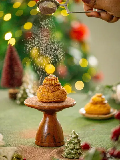 A final action shot from the Christmas pastry series, demonstrating the beautiful effect of the falling powder against the festive lights.