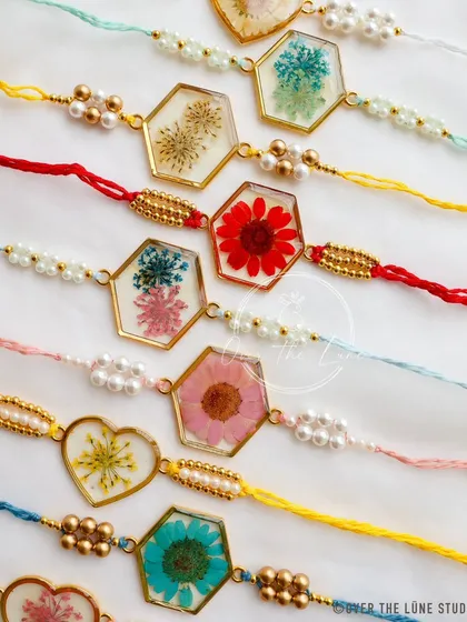 A close-up of my handcrafted Rakhi collection. Each one is made with real, preserved flowers set in resin, featuring unique shapes and colorful threads to celebrate that special bond.