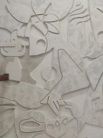 A hand sanding the surface of the 3D mural, a crucial step in achieving the smooth, stone-like finish.
