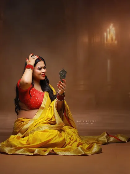 A moment of self-admiration, using a handheld mirror as a prop. The yellow saree and traditional jewelry complete this beautiful, culturally rich portrait.