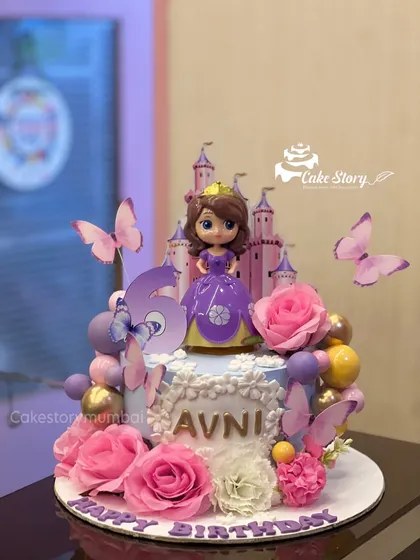 A royal celebration cake featuring Princess Sofia the First. This design includes a castle backdrop, beautiful pink roses, and butterfly accents for a truly enchanting 5th birthday.