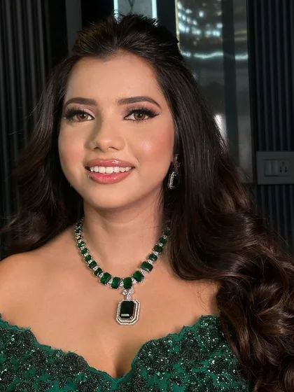 A smiling portrait showcasing the stunning emerald green AD necklace and matching earrings.