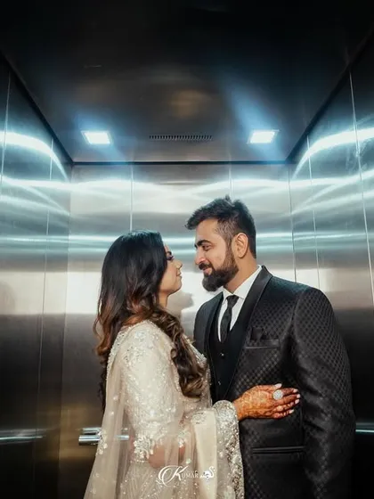 A couple shares a look inside an elevator, a creative shot taken during their engagement party that uses the metallic walls for a modern, edgy feel.