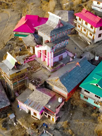 A high altitude drone shot of the Jai Ishwari Maa Temple in Dharech. This aerial perspective reveals the unique, colorful architecture of the temple complex and its placement within the mountain landscape.
