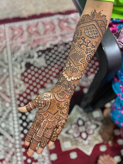 A single arm shot of an engagement mehendi, highlighting the inclusion of the groom's name hidden within the intricate patterns.