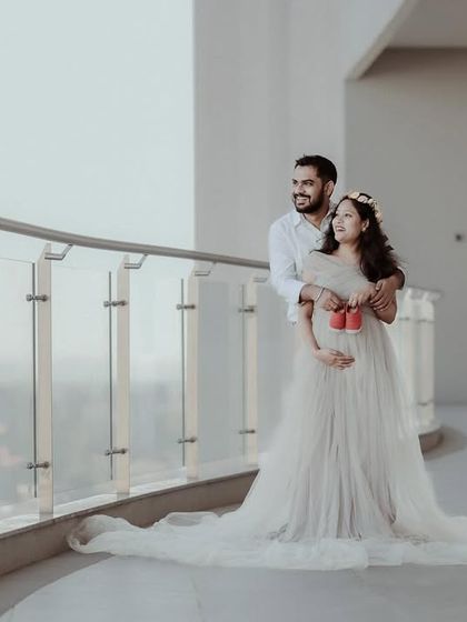 A wide shot of the couple on a balcony, holding a tiny pair of baby shoes. This creative detail adds a powerful storytelling element to their maternity session.