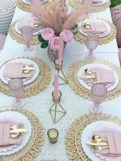 Anything is possible with sunshine and a little bit of pink. This beautiful boho-luxe picnic tablescape features pink glassware, gold cutlery, and woven placemats for a chic daytime event.