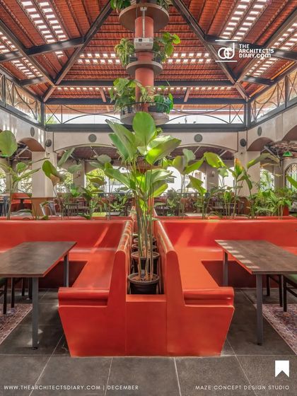 The central seating at Adda 1522 in Bangalore, featuring bold red "katte" style benches. The design merges vintage and tropical styles, with a high, tiled roof and abundant greenery creating an open, airy feel.