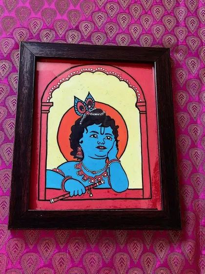 A thoughtful Lord Krishna looking out from a window, holding his flute. This 9x10 inch framed piece has a simple composition that brings a sense of calm and contemplation.