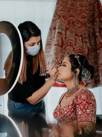 The artist at work. This shot, with the ring light and the bride getting ready, gives a real behind-the-scenes feel of the bridal transformation process.