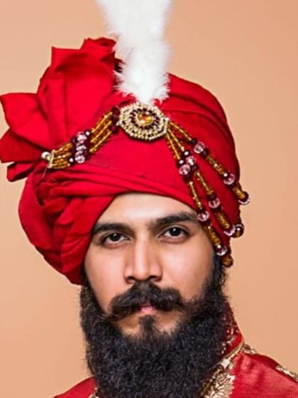 Another view of this majestic red safa, adorned with a 'kalgi' and beaded details. I pay close attention to the folds and shape to ensure the turban is a centerpiece of the groom's attire.