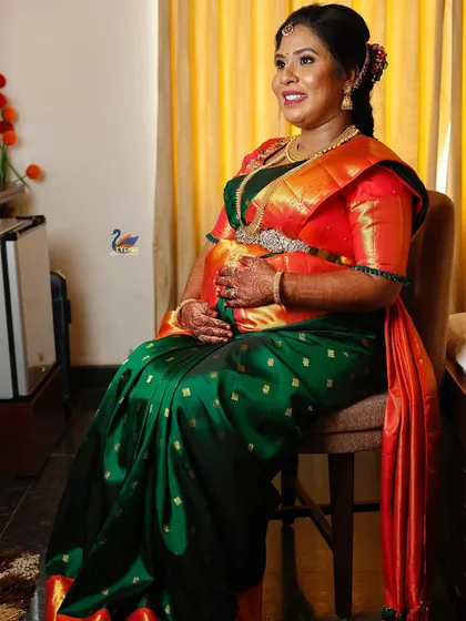A seated portrait of the mother-to-be, looking radiant during her ceremony. This pose is comfortable and elegant, showcasing her traditional attire and jewelry.