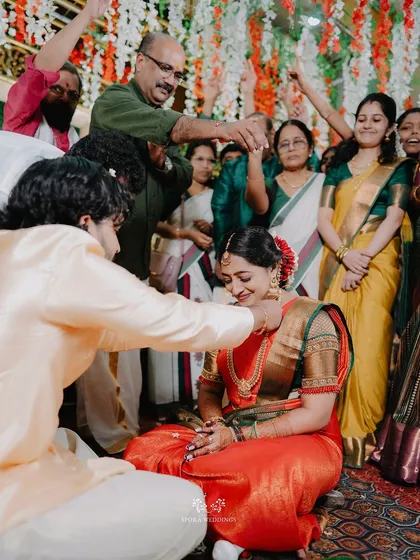 The groom tying the thaali around the bride's neck, a sacred and emotional moment surrounded by the blessings of family.