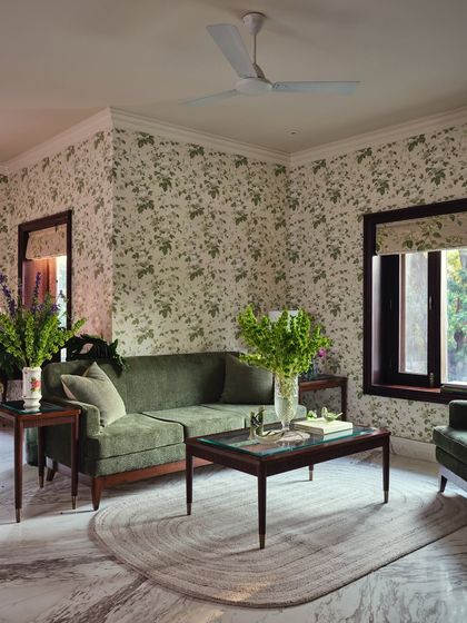 In the master bedroom, the garden climbs the walls. Floral wallpaper, green velvet furniture, and nature-inspired linens create a serene retreat, while preserved wooden architraves hold the room's original cadence.