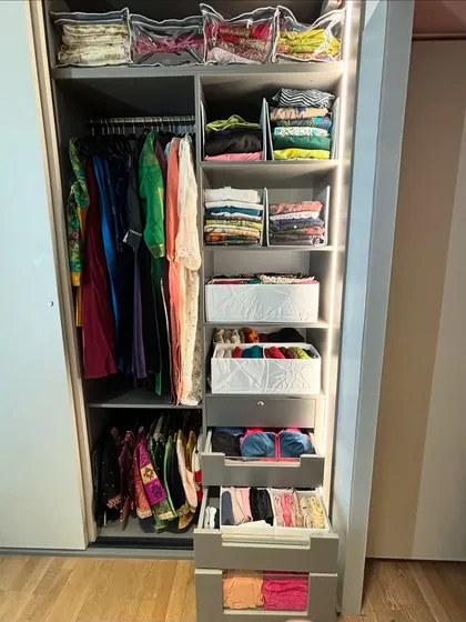 This sliding wardrobe features a mix of hanging space, open shelves with bins, and pull-out drawers for a highly customized system.