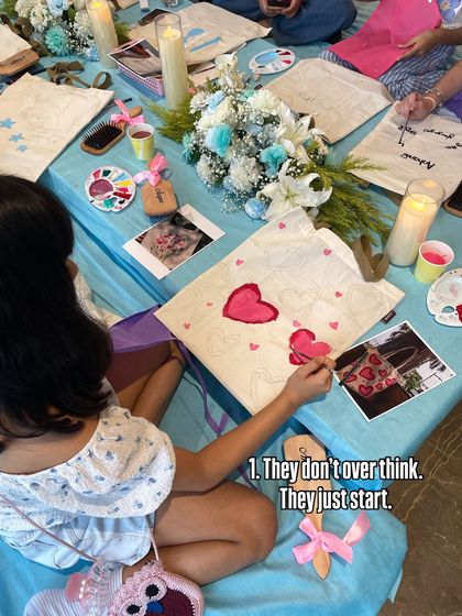 They don't overthink, they just start. This young artist is diving right into painting her tote bag, inspired by the photos and examples around her.