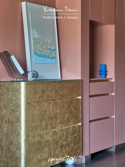 A detail of the living room, showing a custom chest of drawers with a gold leaf finish. This piece adds a touch of glamour and luxury, contrasting with the simple, modern lines of the other furniture.