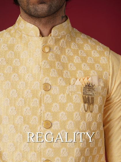 Regality. A close-up on a yellow patterned Nehru jacket, highlighting the fabric and a decorative brooch.