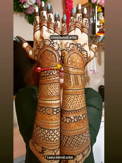 A stunning example of full-coverage bridal mehndi held up for a complete view. The design features classic Indian motifs with geometric patterns filling the arms, creating a beautiful contrast.