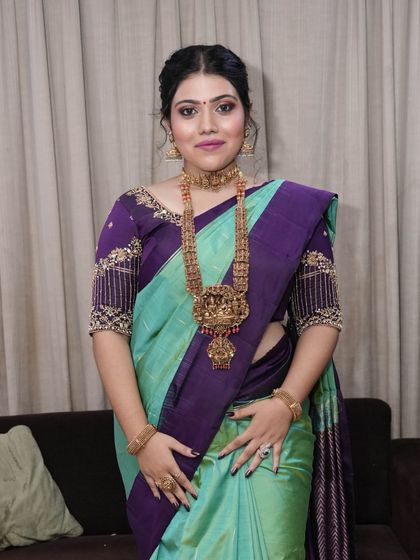 A full-length view of the bride in her stunning turquoise and purple saree. The makeup is balanced to complement the unique color combination of her outfit.