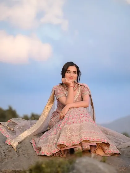 An environmental portrait with the model seated on a rock, her lehenga spread out, against a dramatic sky.