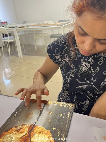 A participant adds delicate gold foil details to her painting, a special technique that adds a touch of magic to any artwork.