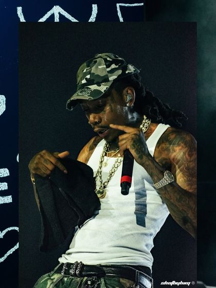 A close-up of Wiz Khalifa during his set, showing his tattoos and chains in detail.