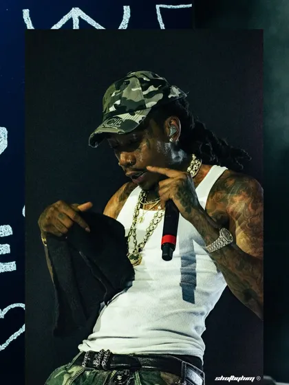 A close-up of Wiz Khalifa during his set, showing his tattoos and chains in detail.