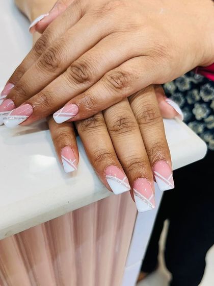 A clean and geometric French manicure. This set has a classic pink base with sharp, angular white tips and a thin silver glitter line for a modern touch.