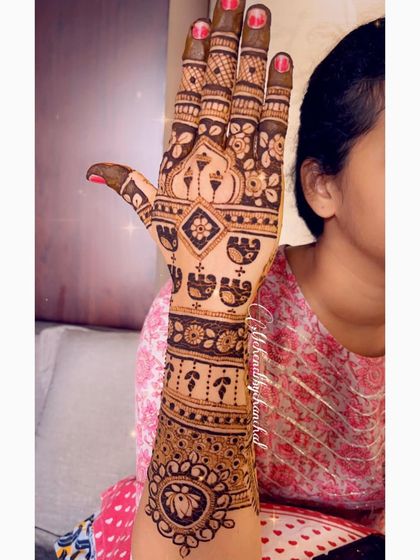 A side view of a bridal mehendi, showing a mix of floral, elephant, and lotus motifs.