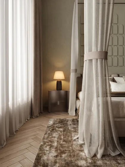 A close-up of the bedside, where a simple lamp casts a warm glow. The sheer curtains of the four-poster bed create a sense of intimacy and calm.