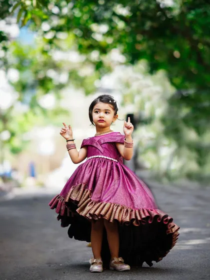 A little princess in a stunning purple gown for her third birthday shoot. This outdoor shot captures her elegance and charm.