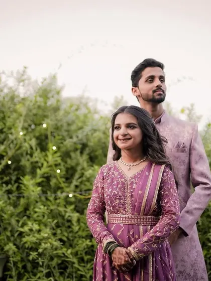 A poised and elegant portrait of the engaged couple against a lush green backdrop, highlighting their beautiful coordinated outfits.