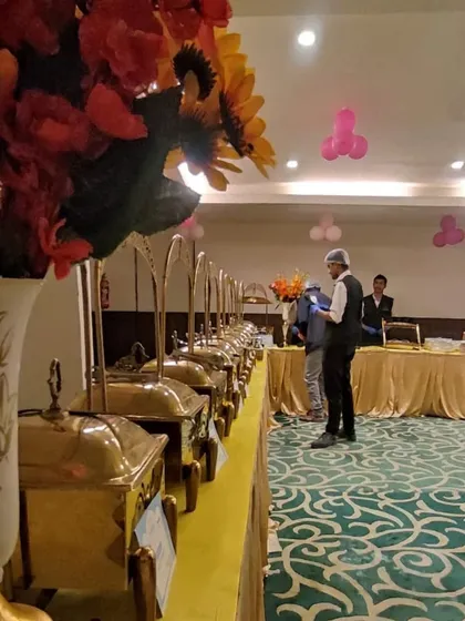 Another view of our buffet line at an indoor party. The elegant floral arrangements and premium brass chafing dishes elevate the presentation for any occasion.