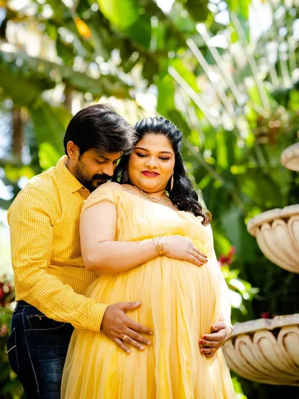 An intimate maternity moment by the garden fountain.