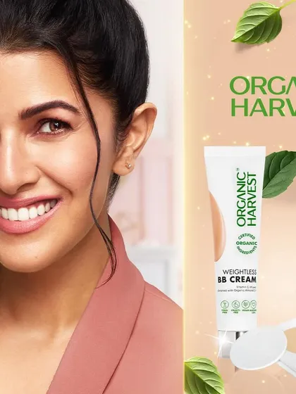 A campaign photograph featuring actress Nimrat Kaur for Organic Harvest. This shot combines a warm, approachable portrait with product imagery for their BB cream and compact, creating an authentic celebrity endorsement for a natural cosmetics brand.