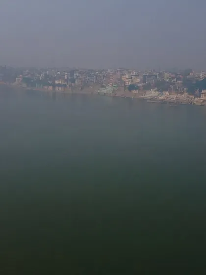 The vast, calm expanse of the Ganga river in the winter morning fog. There's a deep sense of spirituality and timelessness in this view.