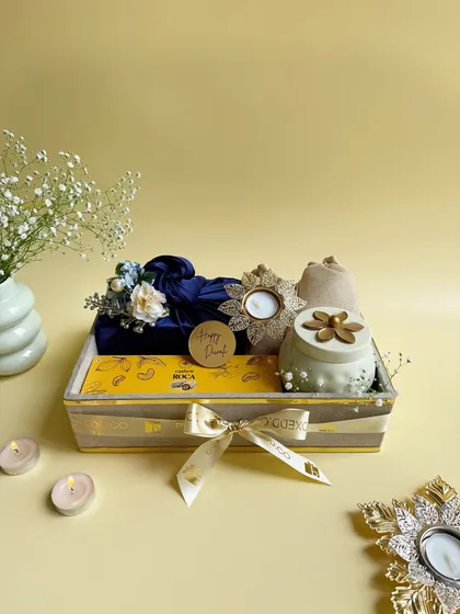 A beautifully arranged Diwali gift tray featuring a scented candle, a traditional diya, and other curated items wrapped in Furoshiki style. The presentation is as important as the gift itself.